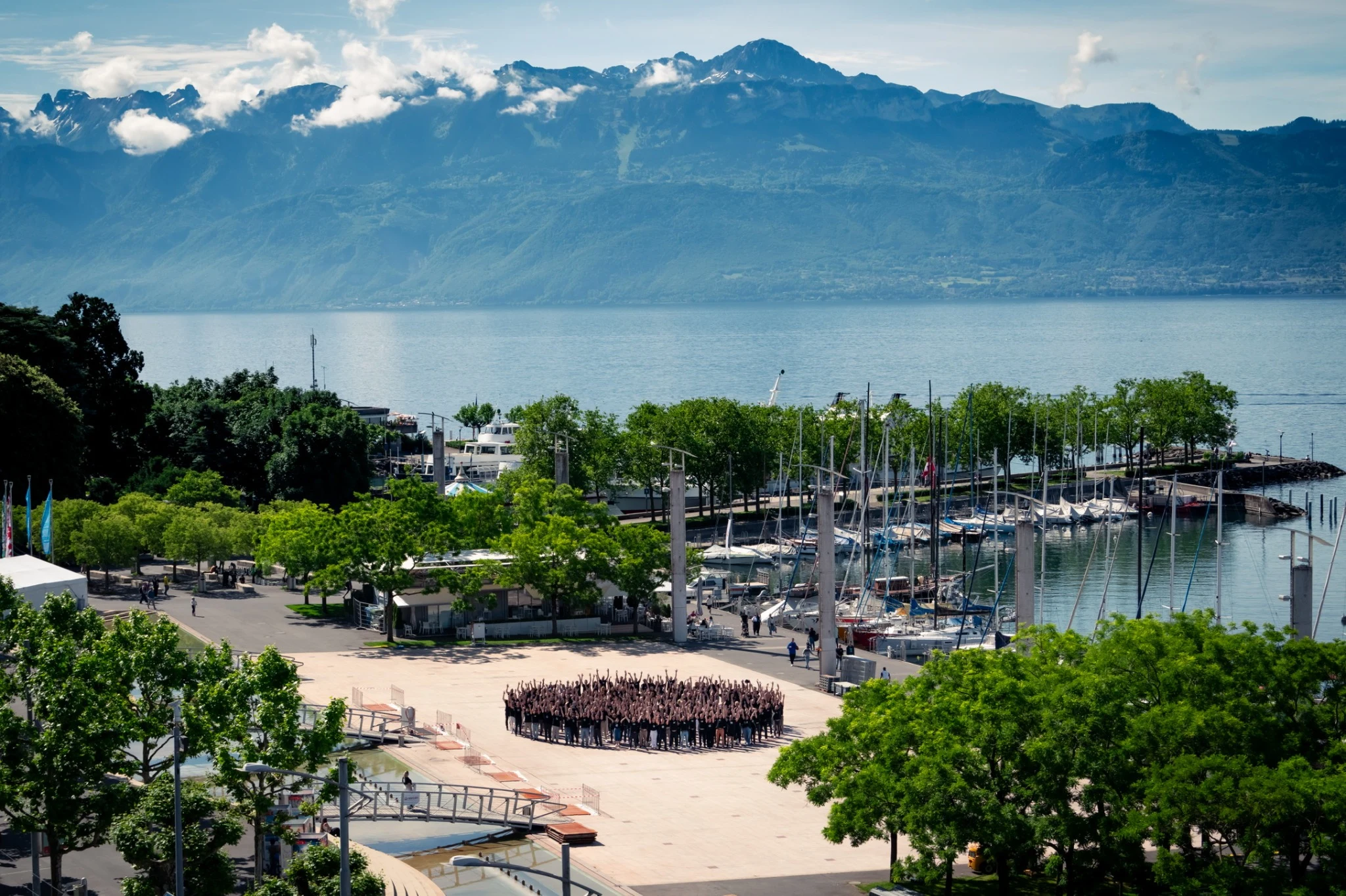 Staff conference group gathered beside the marina in Lausanne, with the lake and mountains beyond